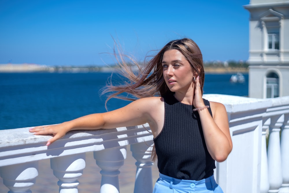 a woman leaning on a railing near the ocean