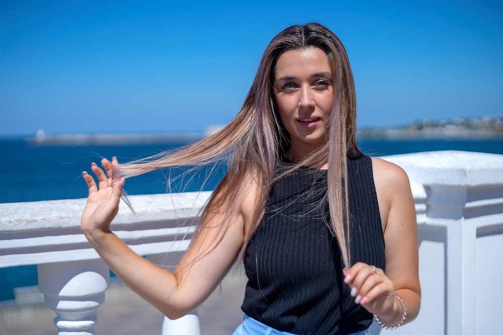 a woman with long hair standing on a balcony near the ocean