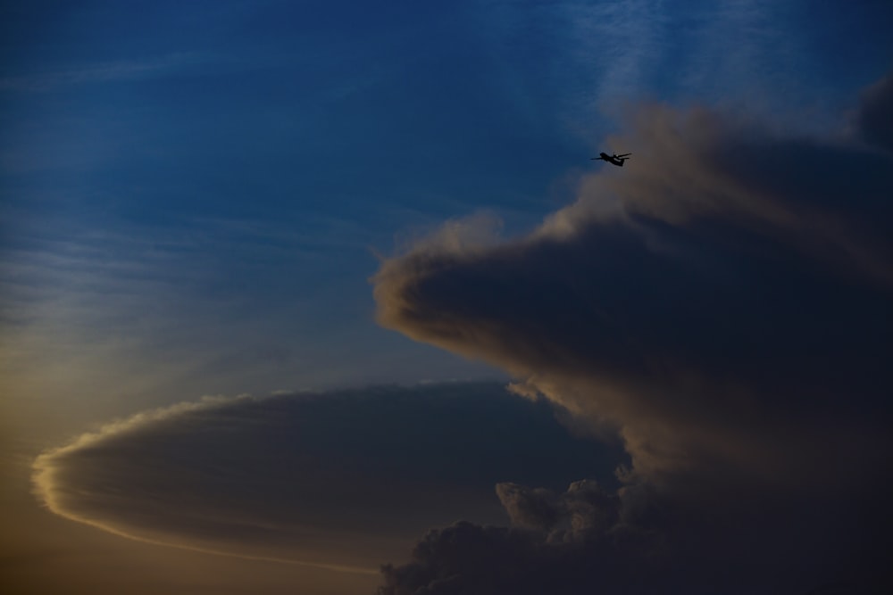 a plane flying through a cloudy sky at sunset