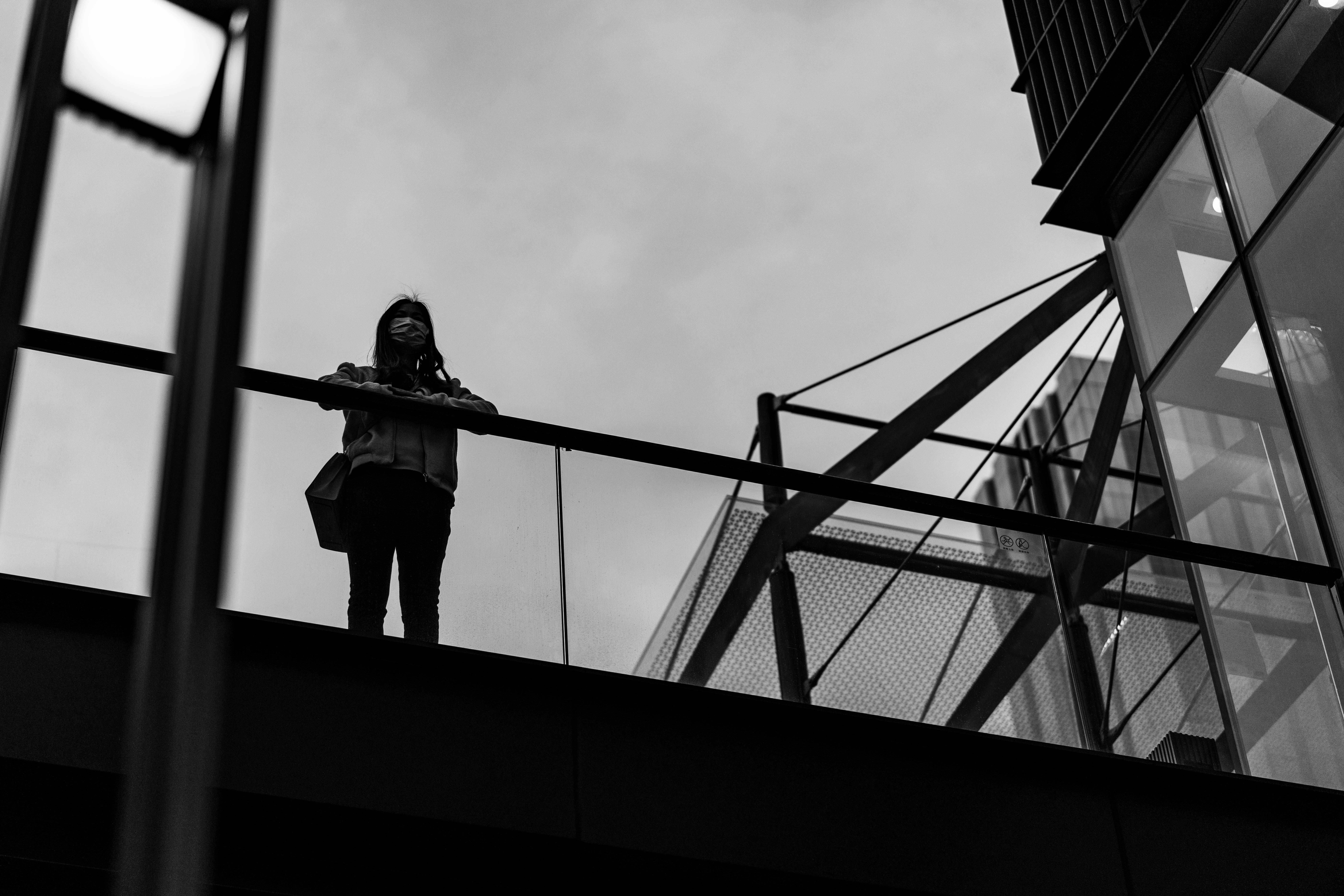a woman standing on a bridge next to a tall building