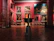 An art gallery interior with several large, classical paintings displayed on deep red walls. The floor is made of polished wood with decorative patterns. Ornate, classical-style furniture and vases are placed around the room. The lighting is soft, highlighting the artwork.