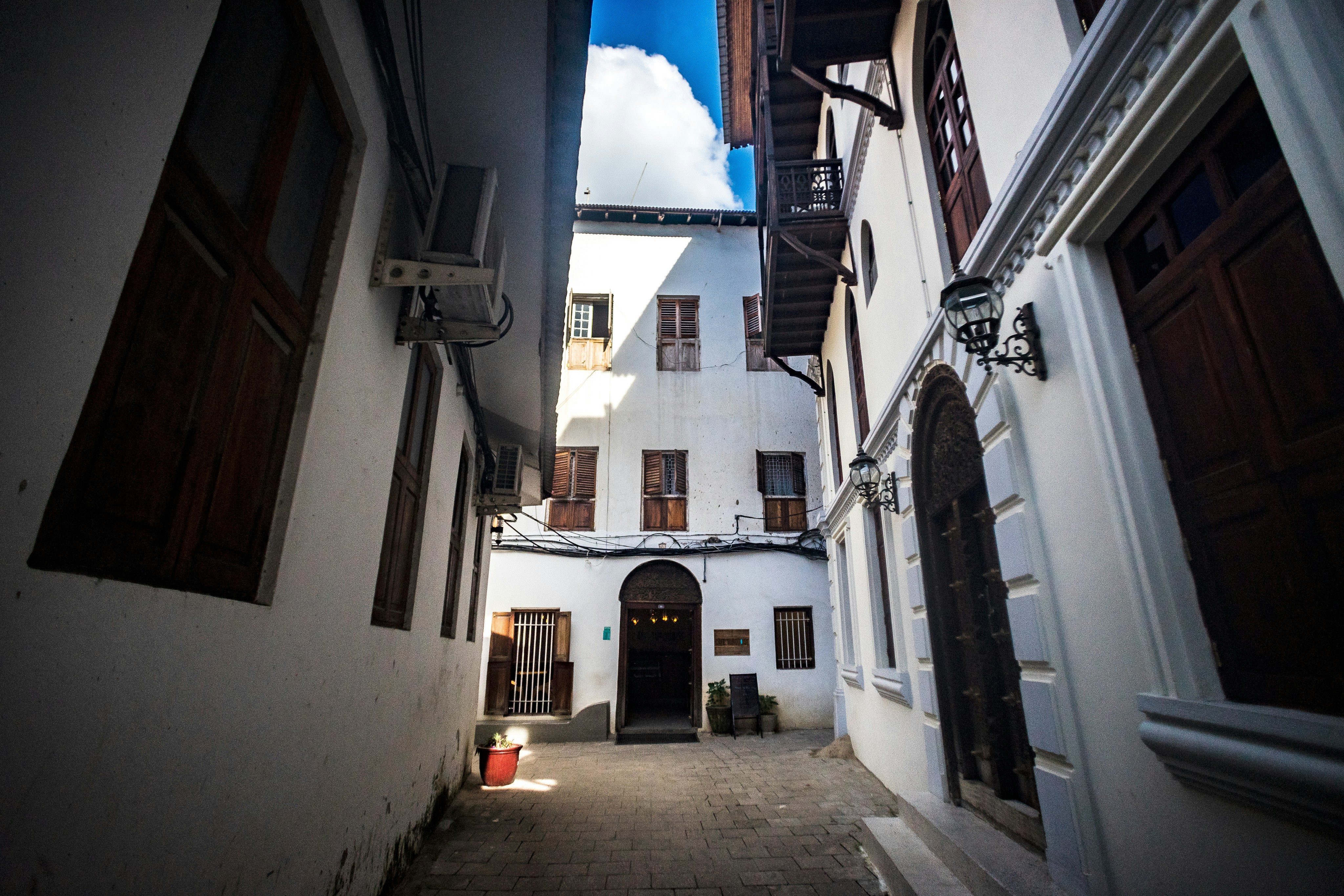 a narrow alley way with a building in the background, Buildings in Stonetown, Zanzibar