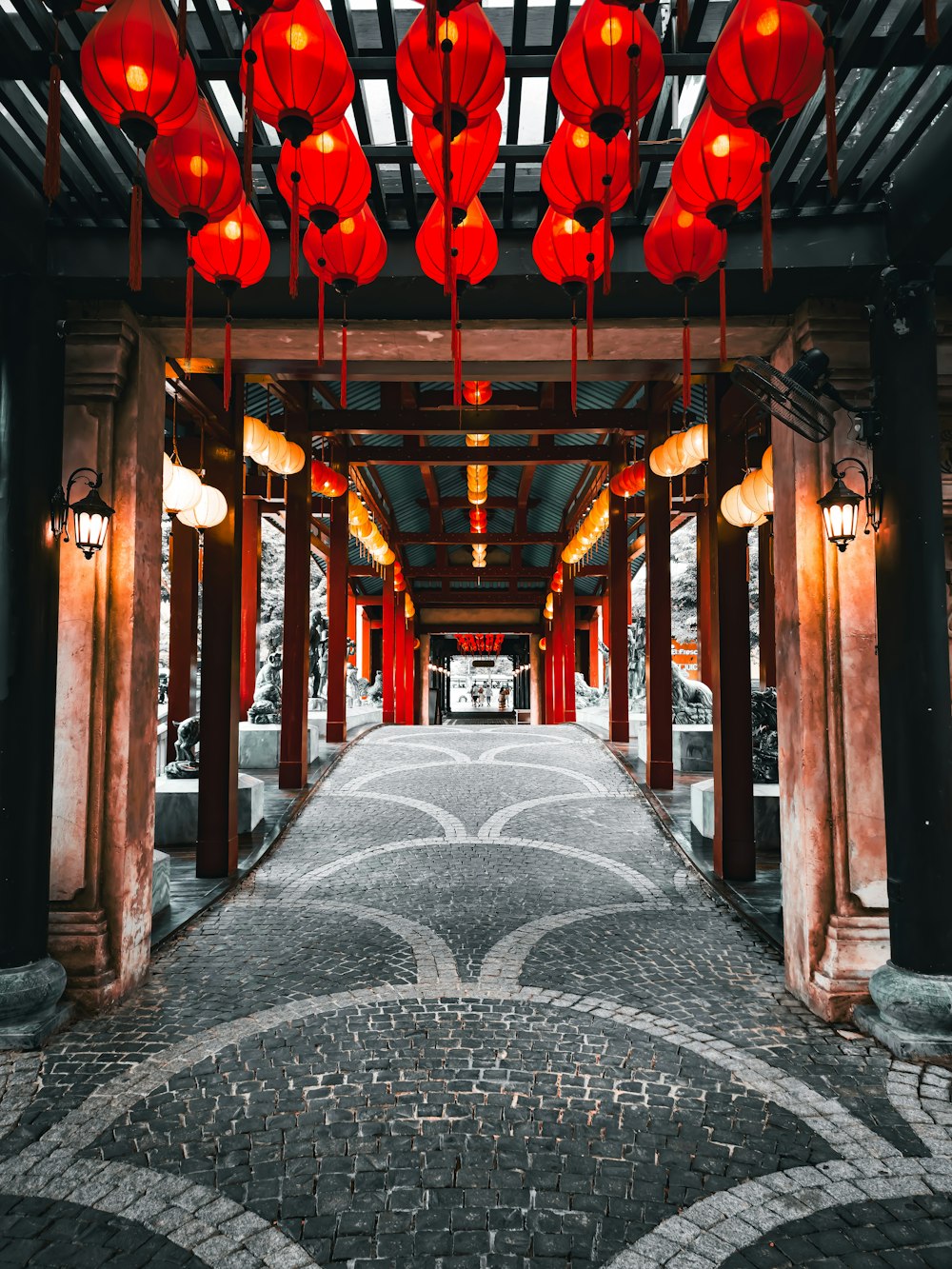 a walkway with red lanterns hanging from the ceiling