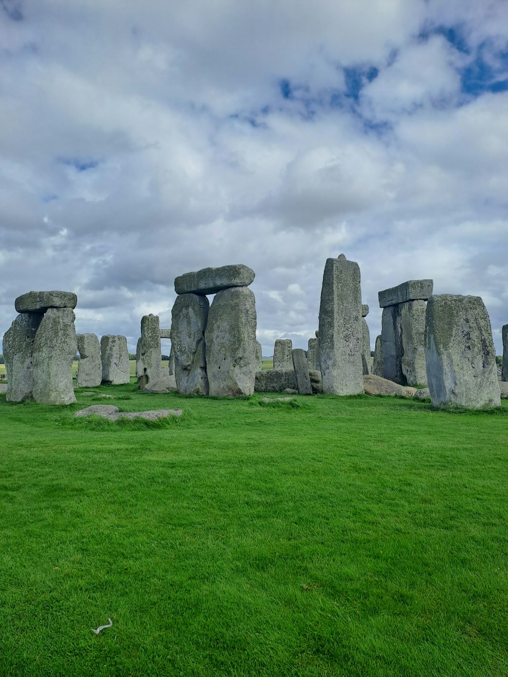 a large stonehenge in a grassy field under a cloudy sky