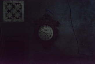 A dimly lit antique clock casting long shadows on a rustic wooden table.