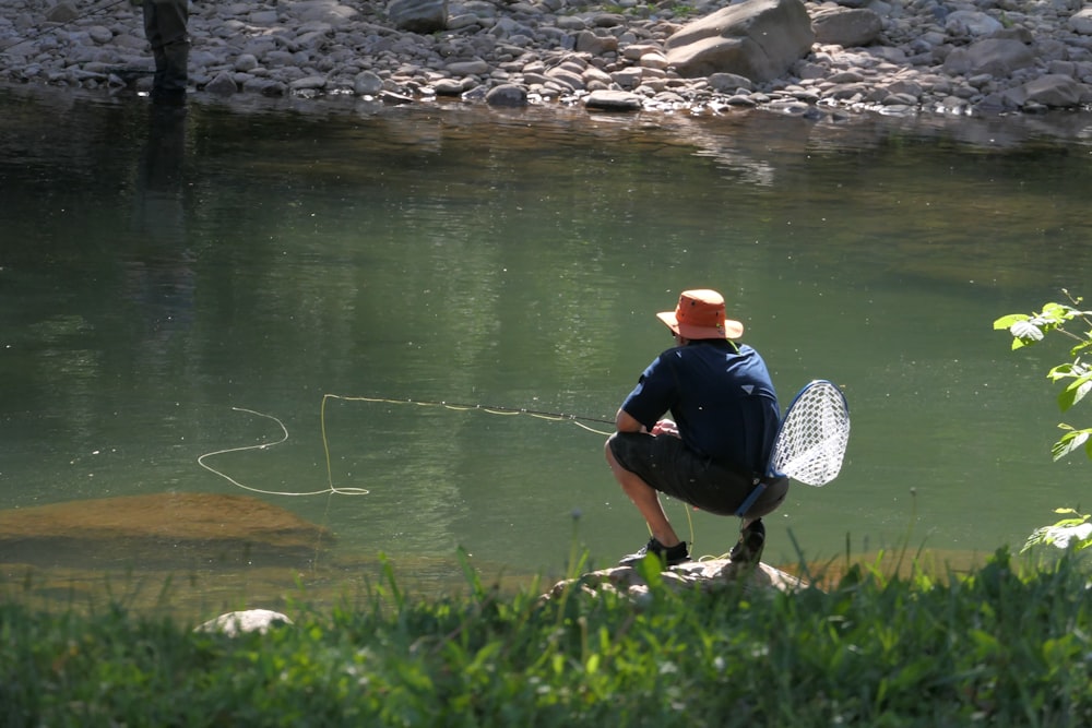 a man kneeling down next to a river holding a fishing net