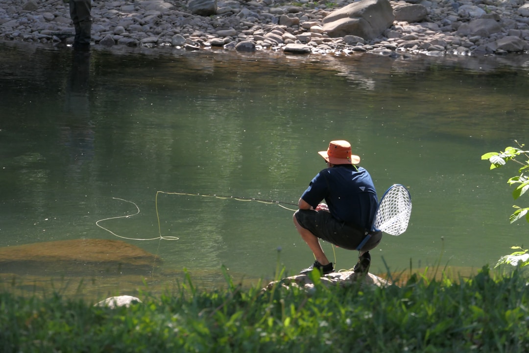 Angler kneeling riverside with his equipment