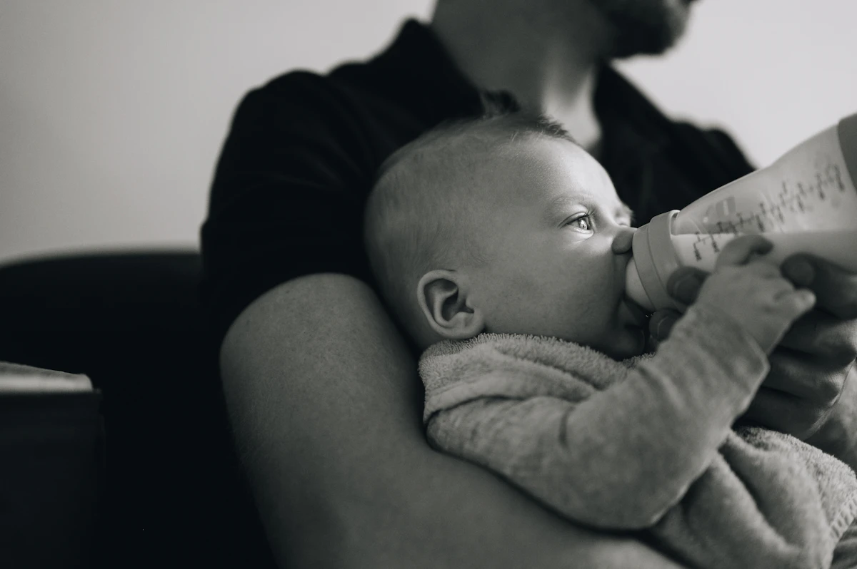 a man holding a baby and feeding it with a bottle