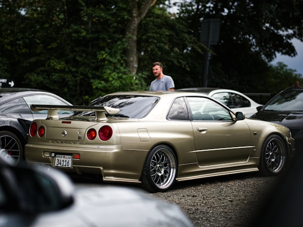 A pristine R33 Skyline GTR parked on a mountain road at sunset, showcasing custom wheels.