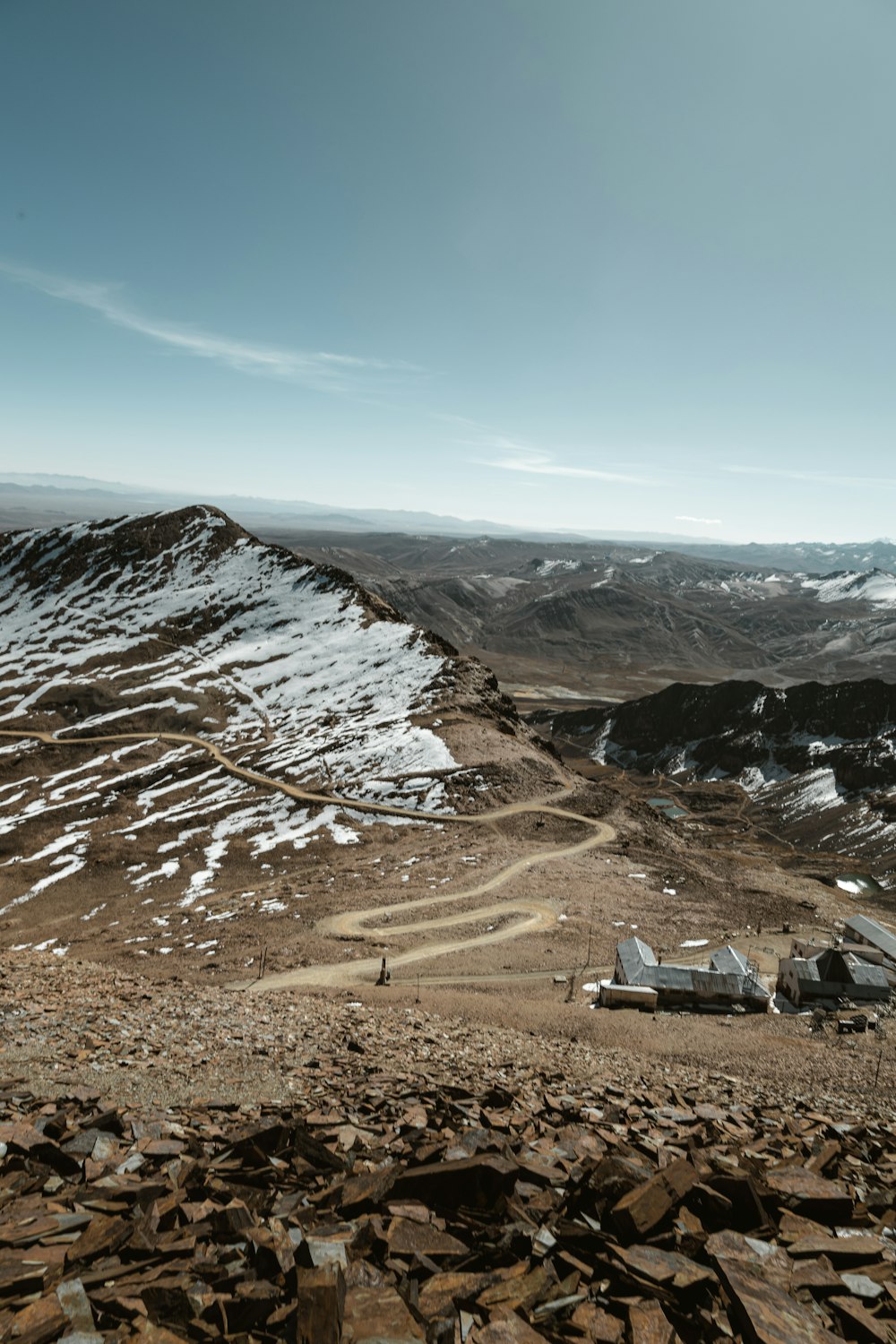 a view of a rocky mountain with a snow covered mountain in the background