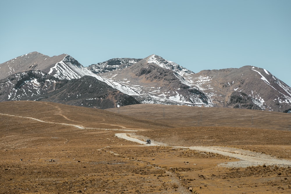 a dirt road in front of a mountain range