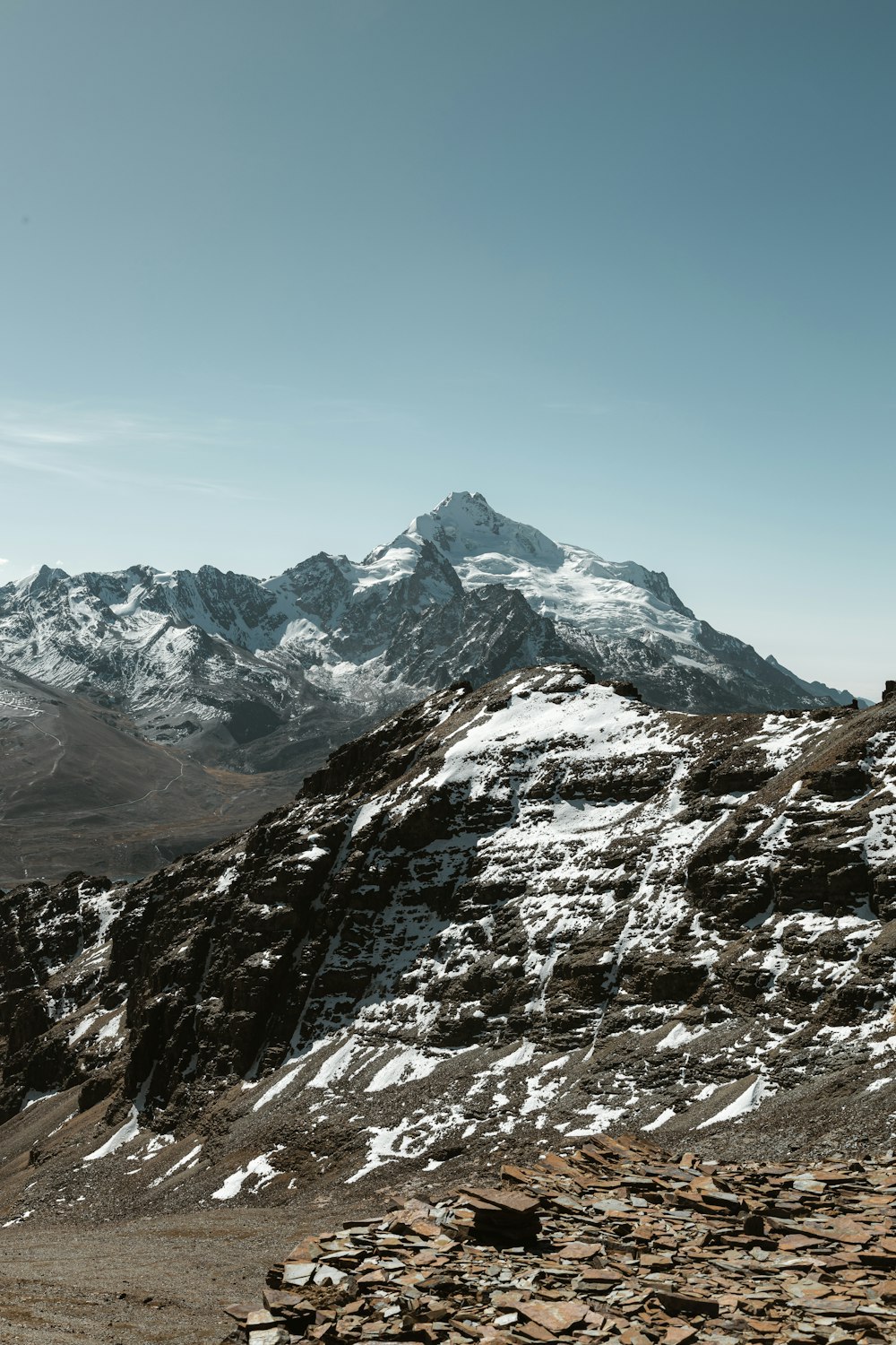 a snowy mountain range with rocks and rocks on the ground