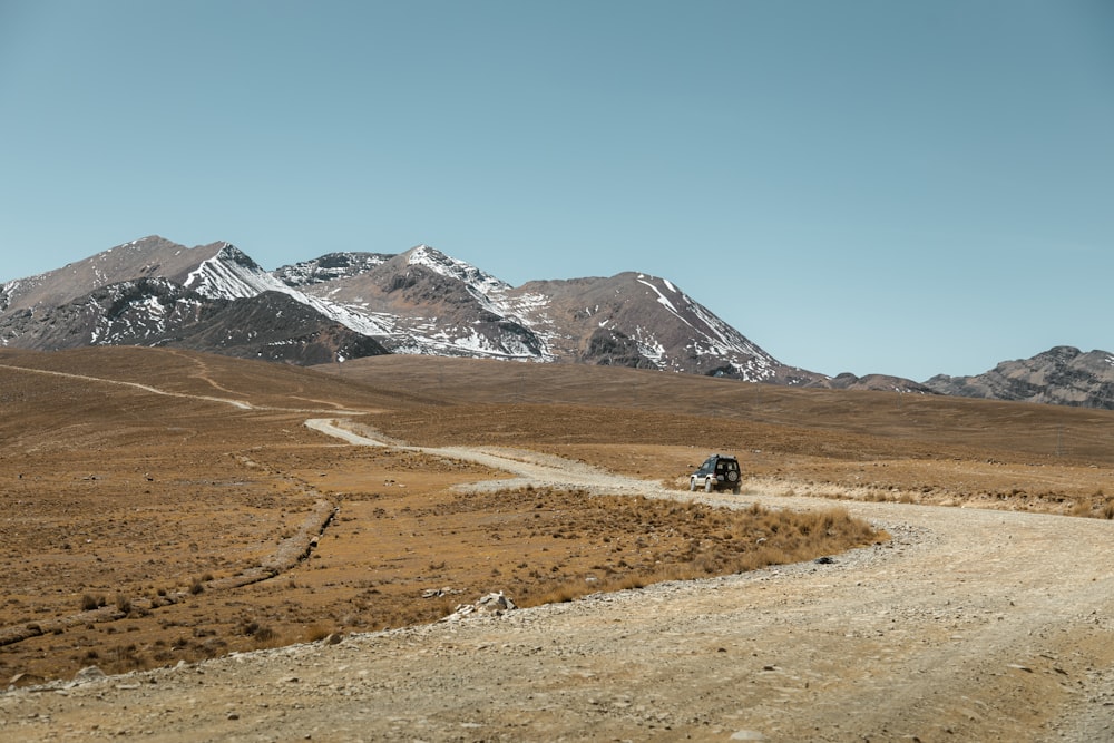 a truck driving down a dirt road in the mountains