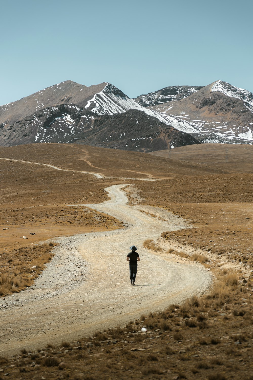 a person walking down a dirt road in the mountains