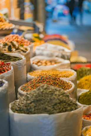 Close-up of aromatic spices spilling from traditional woven sacks on a market stall.