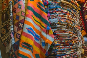 A collection of various handwoven rugs stacked together.