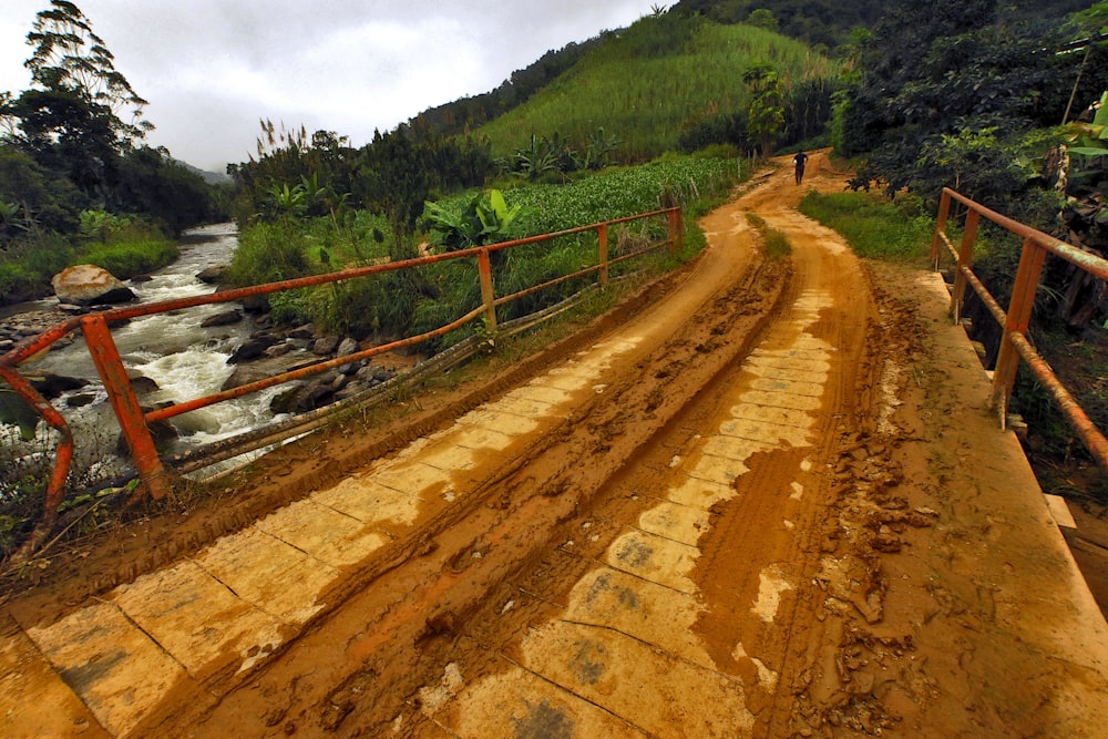 a dirt road going over a bridge over a river