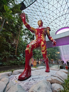 A vibrant display of Iron Man armor models in a sleek, modern exhibition space with red and yellow lighting.
