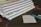 A stack of spiral-bound notebooks lies on a dark surface, accompanied by scattered red petals. Nearby, a small notepad displays the words 'To Do...' next to a teal pen with a gold cap.