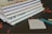 A stack of spiral-bound notebooks lies on a dark surface, accompanied by scattered red petals. Nearby, a small notepad displays the words 'To Do...' next to a teal pen with a gold cap.