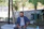 Man enjoying a bottle of Aquavita water outdoors near a park bench.