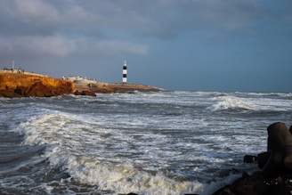 a lighthouse on a rocky shore near the ocean