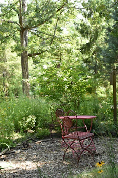 An elegant outdoor loveseat set against a lush garden backdrop.