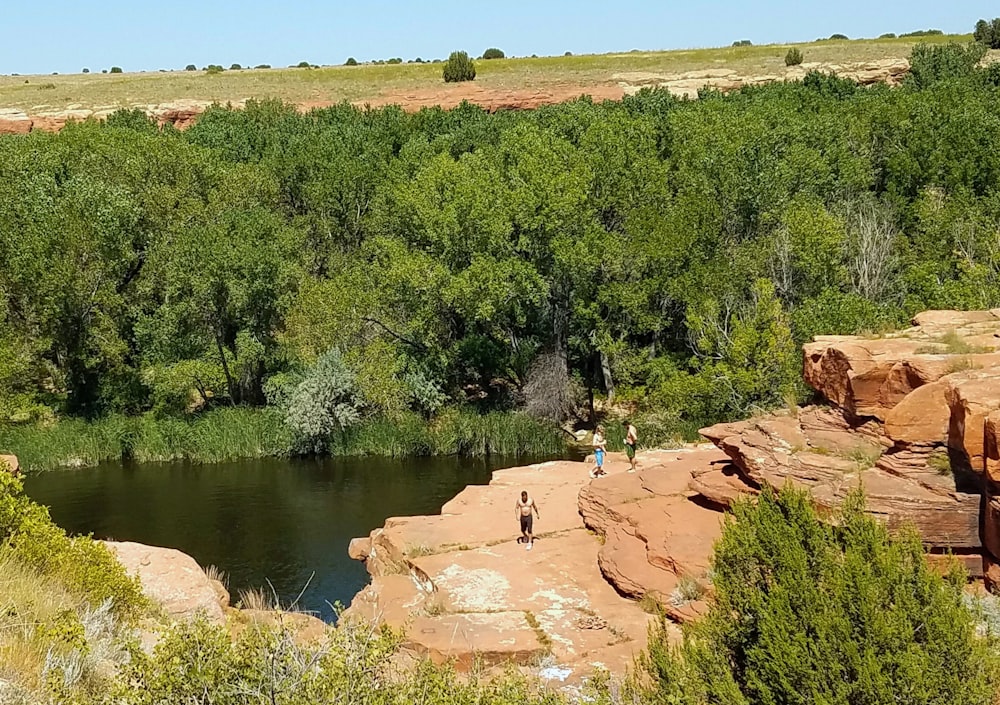 a couple of people standing on top of a cliff next to a river