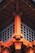 The image shows the detailed architectural design of a traditional Japanese-style structure, featuring vibrant orange wooden beams and intricate fittings. The design emphasizes symmetry and craftsmanship, with a grid-like window section beneath the roof.