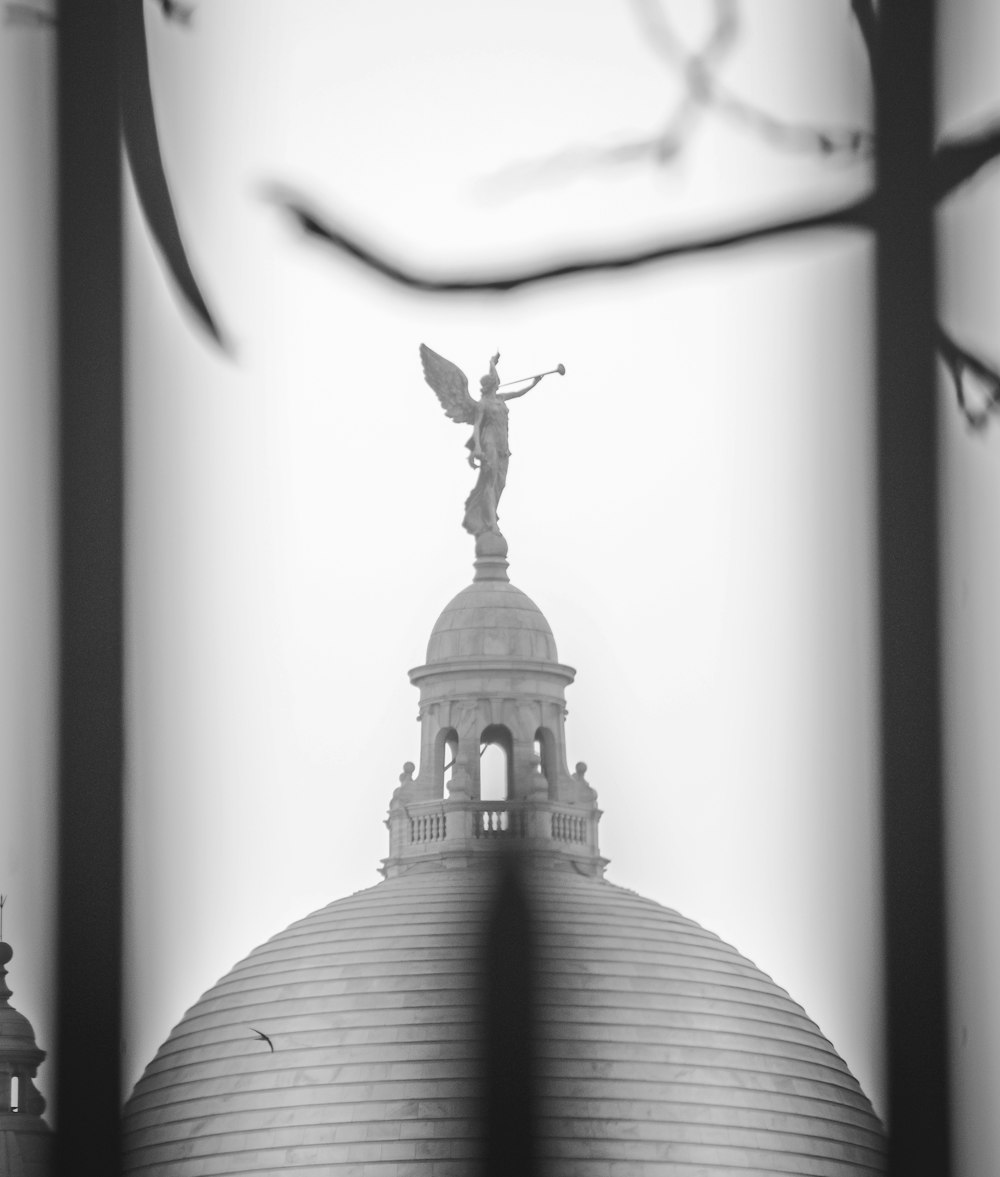 Una foto in bianco e nero di un edificio con una statua in cima