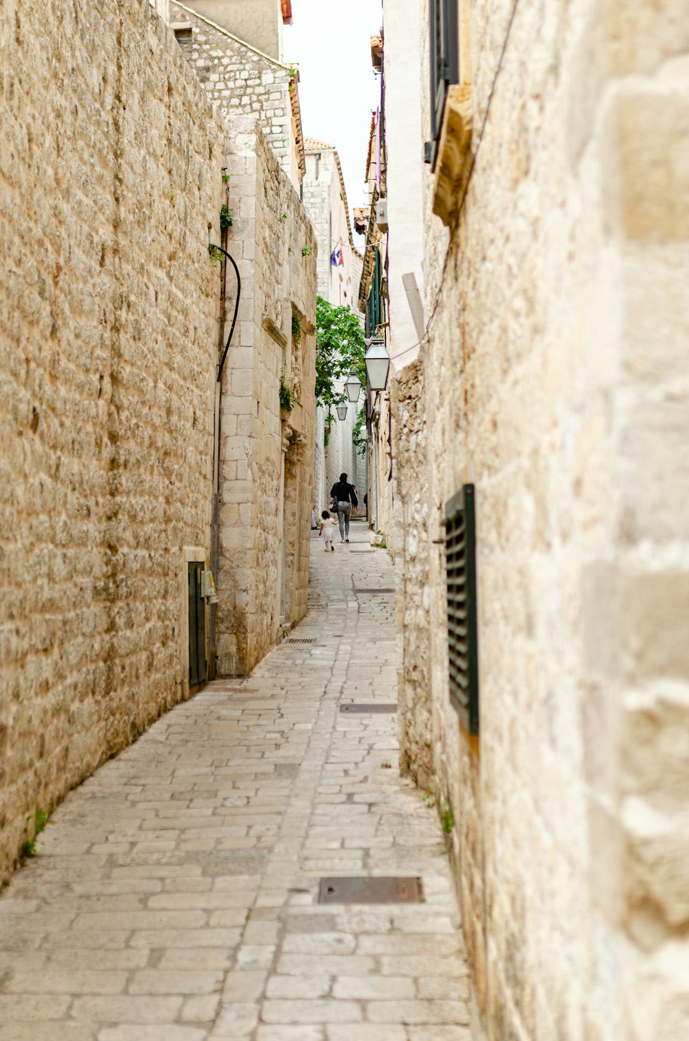 a narrow street with a person walking down it