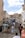A busy stone staircase with tourists climbing and descending. The architecture is historic, featuring a large stone structure with a clock at the top. Several people are gathered on the steps, some seated and others walking. The scene suggests a vibrant tourist destination.