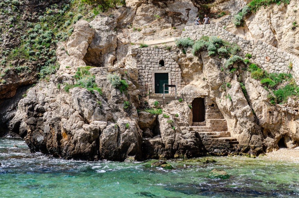 a rocky cliff with a small house built into the side of it
