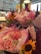 A vibrant display of floral bouquets featuring a variety of brightly colored flowers. The arrangements include sunflowers, dahlias, and delicate lavender spikes, all wrapped in pastel-colored paper. The scene is set in what appears to be a flower shop with a blurred and colorful background.