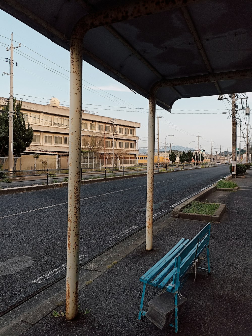 a blue bench sitting on the side of a road