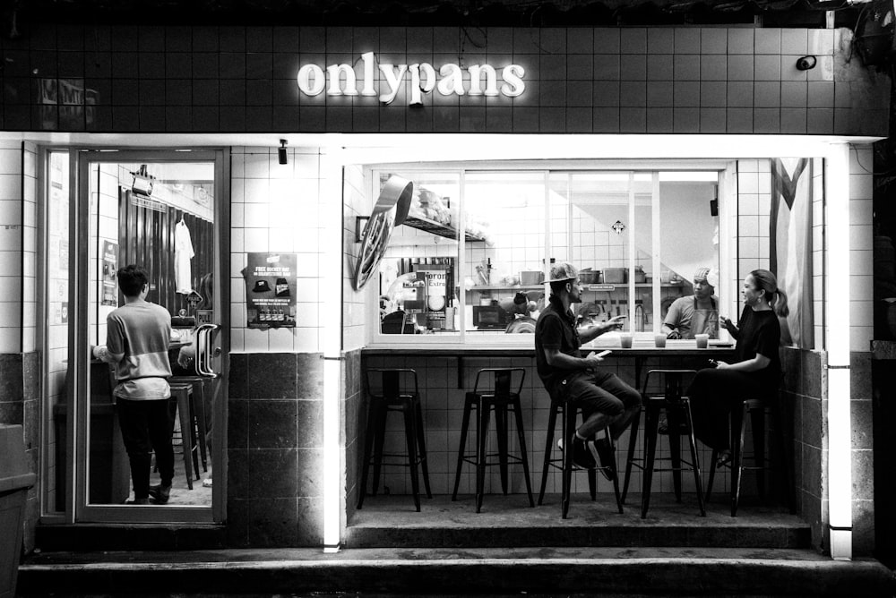 a black and white photo of people sitting at a bar