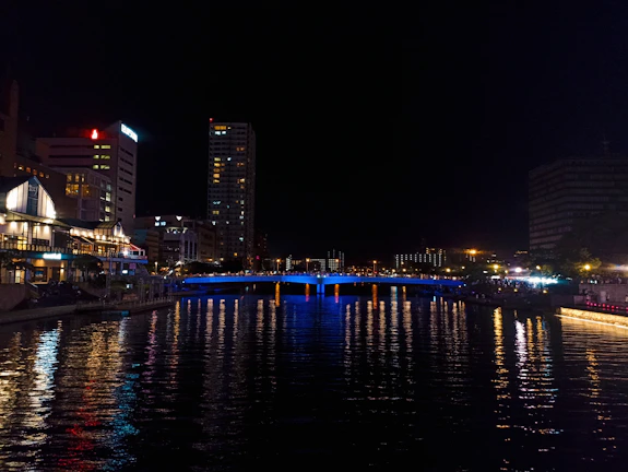 Night view of Aguascalientes city lights reflecting on a calm river.