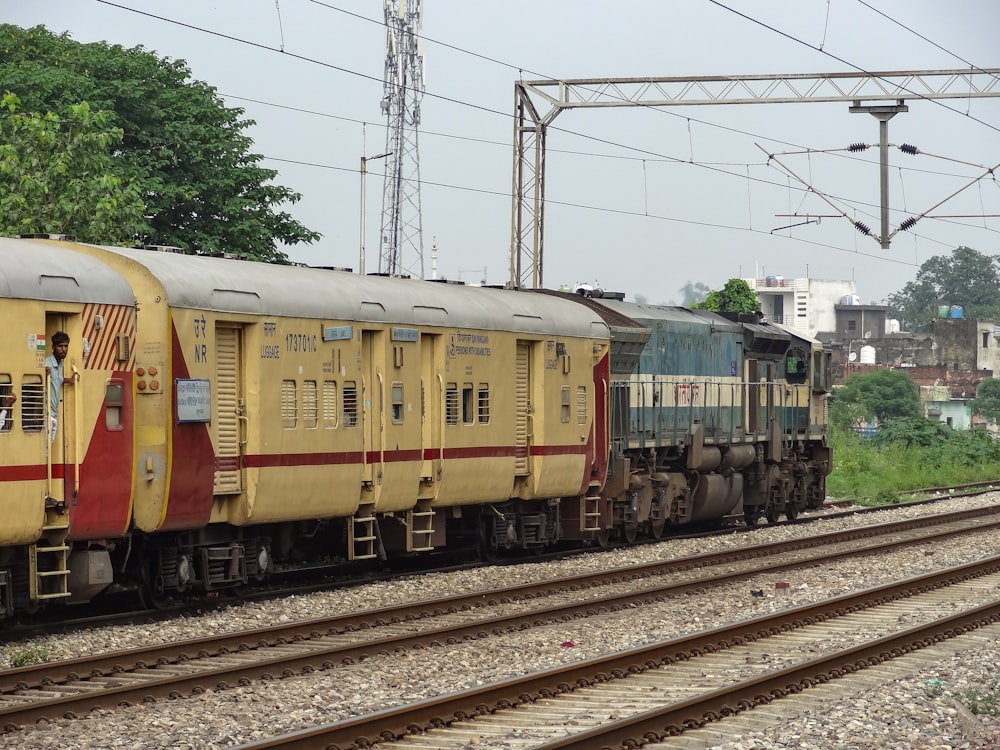 a yellow train traveling down train tracks next to a forest