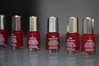 a row of red nail polish bottles sitting on top of a table