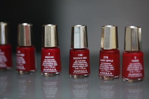 a row of red nail polish bottles sitting on top of a table