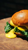Close-up of a juicy, freshly grilled hamburger with melted cheese and fresh lettuce on a rustic wooden table.