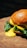 Close-up of a juicy hamburger with melted cheese and fresh toppings on a rustic wooden table.