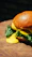Close-up of a gourmet burger with melted cheese and fresh lettuce on a rustic wooden table.