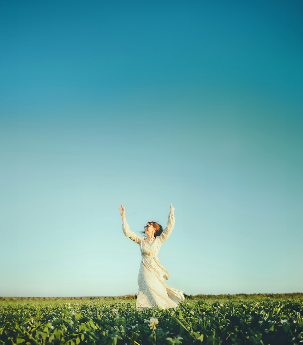 a woman in a white dress standing in a field