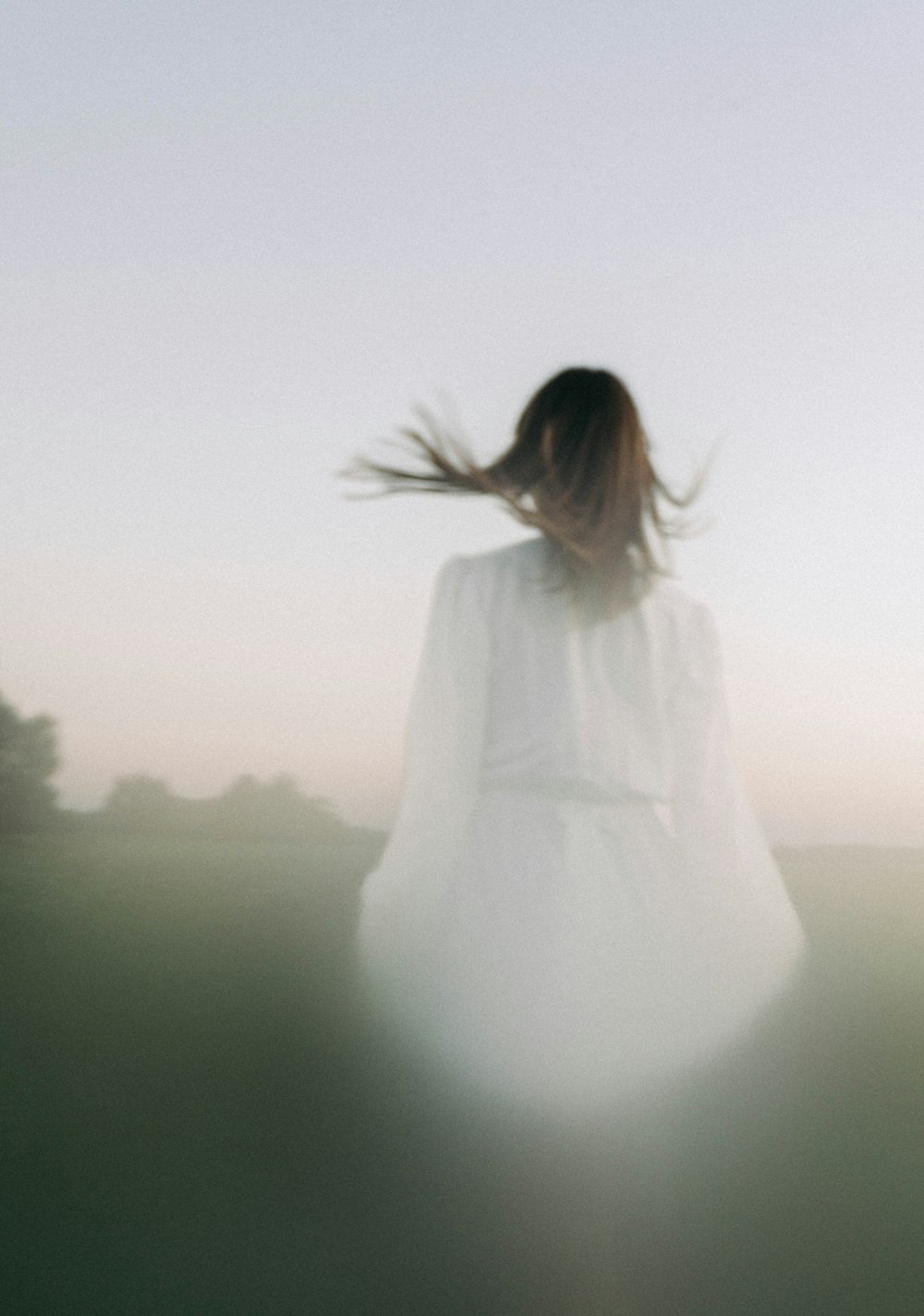 a woman in a white dress walking through a field