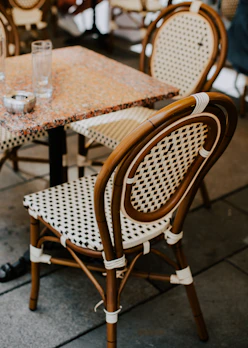 Elegant rattan dining set with a glass table and woven chairs.
