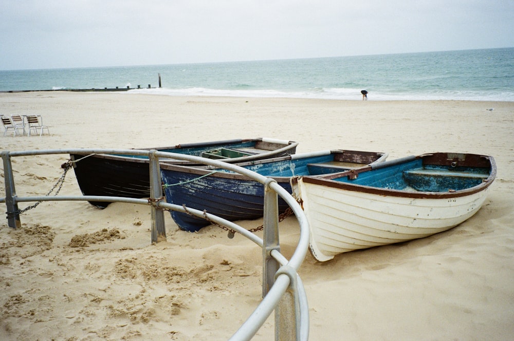 a couple of boats sitting on top of a sandy beach