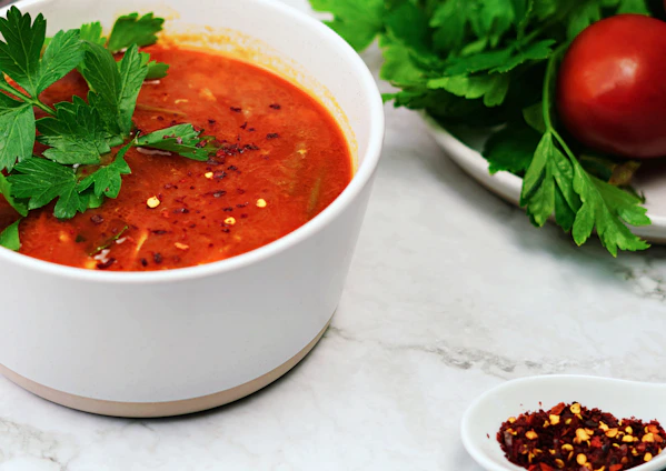 a bowl of tomato soup with parsley on top