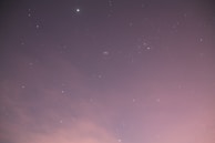 An original illustration showing a starry night sky with soft pink and violet hues, evoking calm and hope.