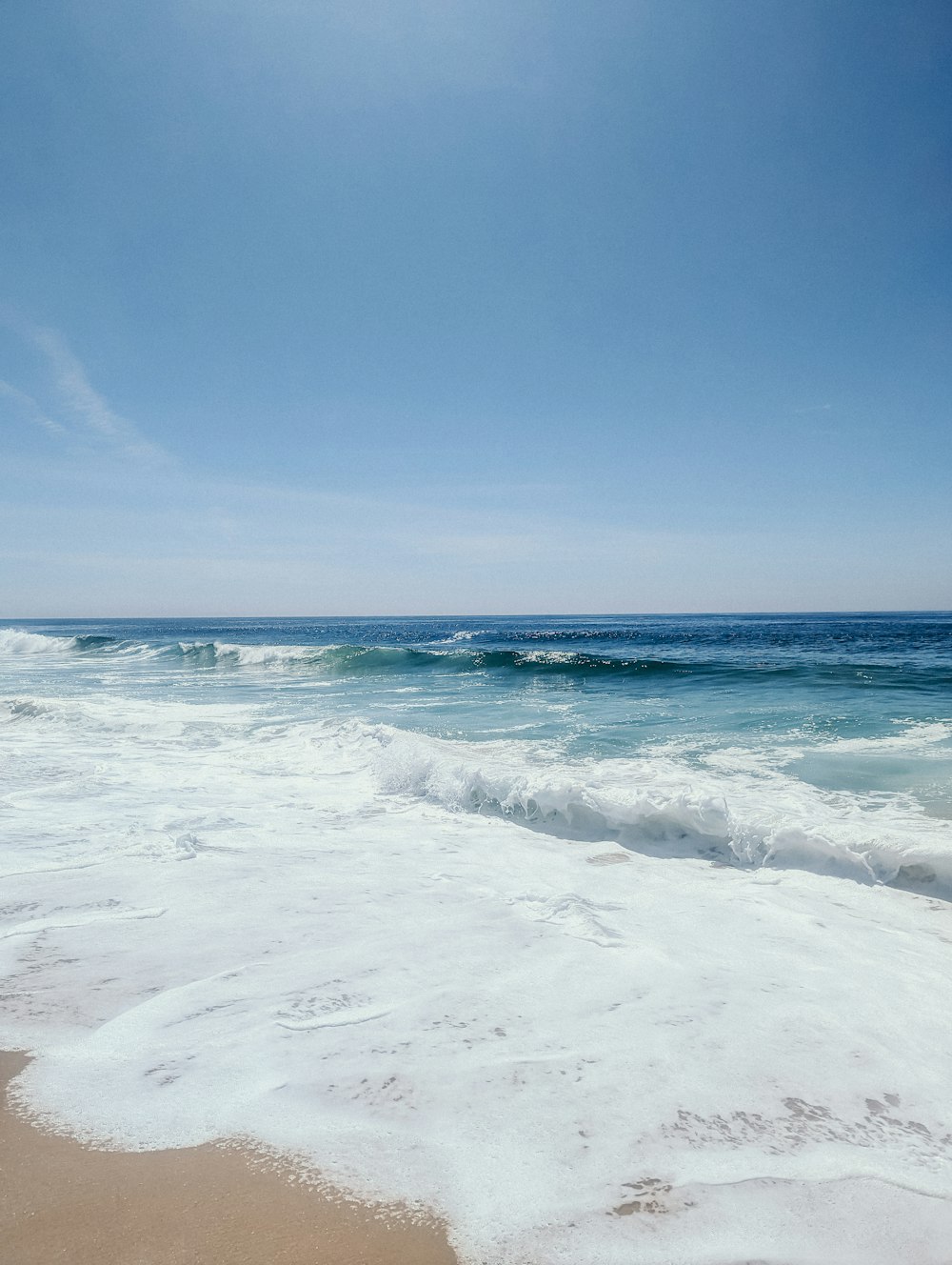 a sandy beach with waves coming in to shore